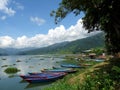 Colourful rowing boats on Phewa Lake, Pokhara, Nepal with mountains Royalty Free Stock Photo