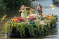 Colourful canal parade of flower and vegetables decorated boats with cheerful dressed up singing and dancing people