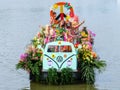 Colourful canal parade of flower and vegetables decorated boats with cheerful dressed up singing and dancing people