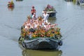 Colourful canal parade of flower and vegetables decorated boats with cheerful dressed up singing and dancing people