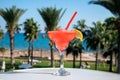 Colourful cold Strawberry daiquiri cocktail drink served in glass at outdoor cafe overlooking blue sea and palm trees, relax and Royalty Free Stock Photo