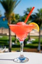 Colourful cold Strawberry daiquiri cocktail drink served in glass at outdoor cafe overlooking blue sea and palm trees, relax and Royalty Free Stock Photo