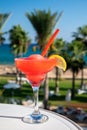 Colourful cold Strawberry daiquiri cocktail drink served in glass at pool bar overlooking blue pool, sea and palm trees, relax and Royalty Free Stock Photo