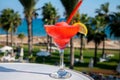 Colourful cold Strawberry daiquiri cocktail drink served in glass at pool bar overlooking blue pool, sea and palm trees, relax and Royalty Free Stock Photo