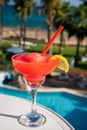 Colourful cold Strawberry daiquiri cocktail drink served in glass at pool bar overlooking blue pool, sea and palm trees, relax and Royalty Free Stock Photo