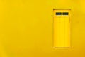 Colourful colonial Caribbean tropical house yellow facade closed window in bright and intense yellow simple wall house background.