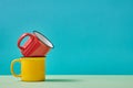 Colourful cups. Teacup. Coffee time. Tea-time. Crockery. Yellow and red mugs on table on blue background. Copy space Royalty Free Stock Photo