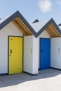 Colourful doors of yellow and blue, with each one being numbered individually, of white beach houses on a sunny day