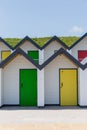 Colourful doors of yellow and green, with each one being numbered individually, of white beach houses on a sunny day