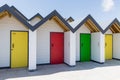 Colourful doors of yellow, green and red, with each one being numbered individually, of white beach houses on a sunny day