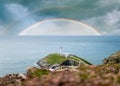 Colourful double rainbows in seascape over the ocean horizon with storm clouds dramatic sky and white lighthouse south stack Royalty Free Stock Photo