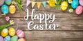 Colourful Easter background with Happy Easter Text decorated eggs and spring flowers, on a rustic wooden background