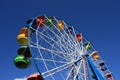 Colourful Ferris Wheel over the blue clear sky with red, green, blue and yellow cabins