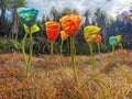 Colourful glass art flower installation on a field on a cloudy day