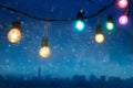 Colourful glowing christmas lights in snowfall on the dark blue city Royalty Free Stock Photo