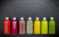 Colourful healthy smoothies and juices in bottles on dark stone background .