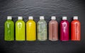 Colourful healthy smoothies and juices in bottles on dark stone background .