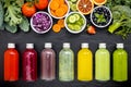 Colourful healthy smoothies and juices in bottles with fresh tropical fruit and superfoods on dark stone background with copy