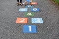 Colourful hopscotch playground markings numbers on stone at pavement with people playing