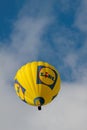 A colourful hot air balloon with advertisement flying high in the summer sky