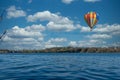 Colourful hot air balloon flies over the blue water of a lake Royalty Free Stock Photo