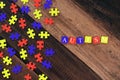 Colourful jigsaw puzzle and alphabet tiles with AUTISM word on wooden table Royalty Free Stock Photo