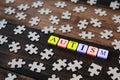 Colourful jigsaw puzzle and alphabet tiles with AUTISM word on wooden table Royalty Free Stock Photo