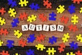 Colourful jigsaw puzzle and alphabet tiles with AUTISM word on wooden table Royalty Free Stock Photo