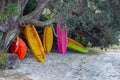 Colourful Kayaks stacked under a tree