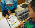 Colourful letters on the book as reference for the child to type into the braille typwriter