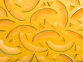 Colourful pattern made of ripe melon slices on yellow backdrop.