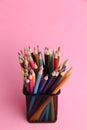 Colourful pencils in the metal pencil holder on the pink background