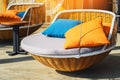 Colourful pillows on modern daybed. Brown rattan loungers with orange and blue pillows hanging with rope by relaxing terrace.