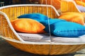 Colourful pillows on modern daybed. Brown rattan loungers with orange and blue pillows hanging with rope by relaxing terrace.