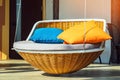 Colourful pillows on modern daybed. Brown rattan loungers with orange and blue pillows hanging with rope by relaxing terrace.