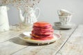 Stack of colourful pink pancakes poured honey.