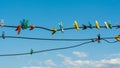 Colour plastic clothespins clothes pegs on outdoor wire laundry wash line against a vivid clear blue sky Royalty Free Stock Photo