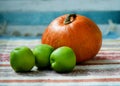 Colourful pumpkin and three green apples on the indian rug. Royalty Free Stock Photo