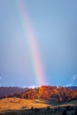 Colourful rainbow aver autumn forest landscape after the storm in the mountains or Roumania , vertical photo landscape