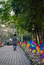 Colourful rainbow pinwheel in the park with people walking along the pathway.