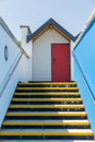 Colourful red door, with each one being numbered individually, of white beach houses on a sunny day, a view looking up the yellow