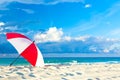 Colourful red and white umbrella on the ocean beach with beautiful blue sky and clouds. Relaxation, vacation idyllic background Royalty Free Stock Photo
