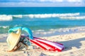 Colourful red and white umbrella with straw hat, beach bag and blue bikini bra swimsuit against the ocean beach with beautiful Royalty Free Stock Photo