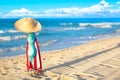 Colourful red and white umbrella with straw hat and blue bikini bra swimsuit against the ocean beach with beautiful blue sky and Royalty Free Stock Photo