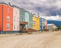 Colourful row of accommodation units on dusty street with dark clouds overhead