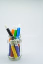 Colourful school supplies in a transparent jar, stationery on white background. Royalty Free Stock Photo