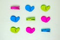 Colourful set of nine plastic clothespins or pegs on a light green sparkling background with copy field. View from abov
