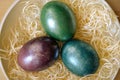 Colourful shiny easter eggs in the bowl with hay. Royalty Free Stock Photo