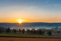 Colourful sunrise on a summer morning with a little fog on the ground and spectacular views over the Dutch hillside in Limburg