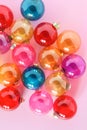 Colourful translucent glass Christmas baubles on pink background. Top view